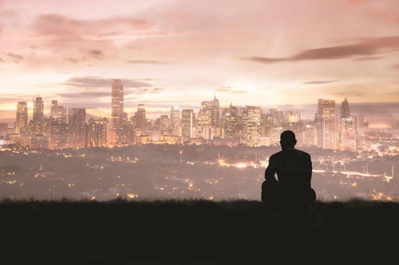 man silhouette sitting overlooking city evening